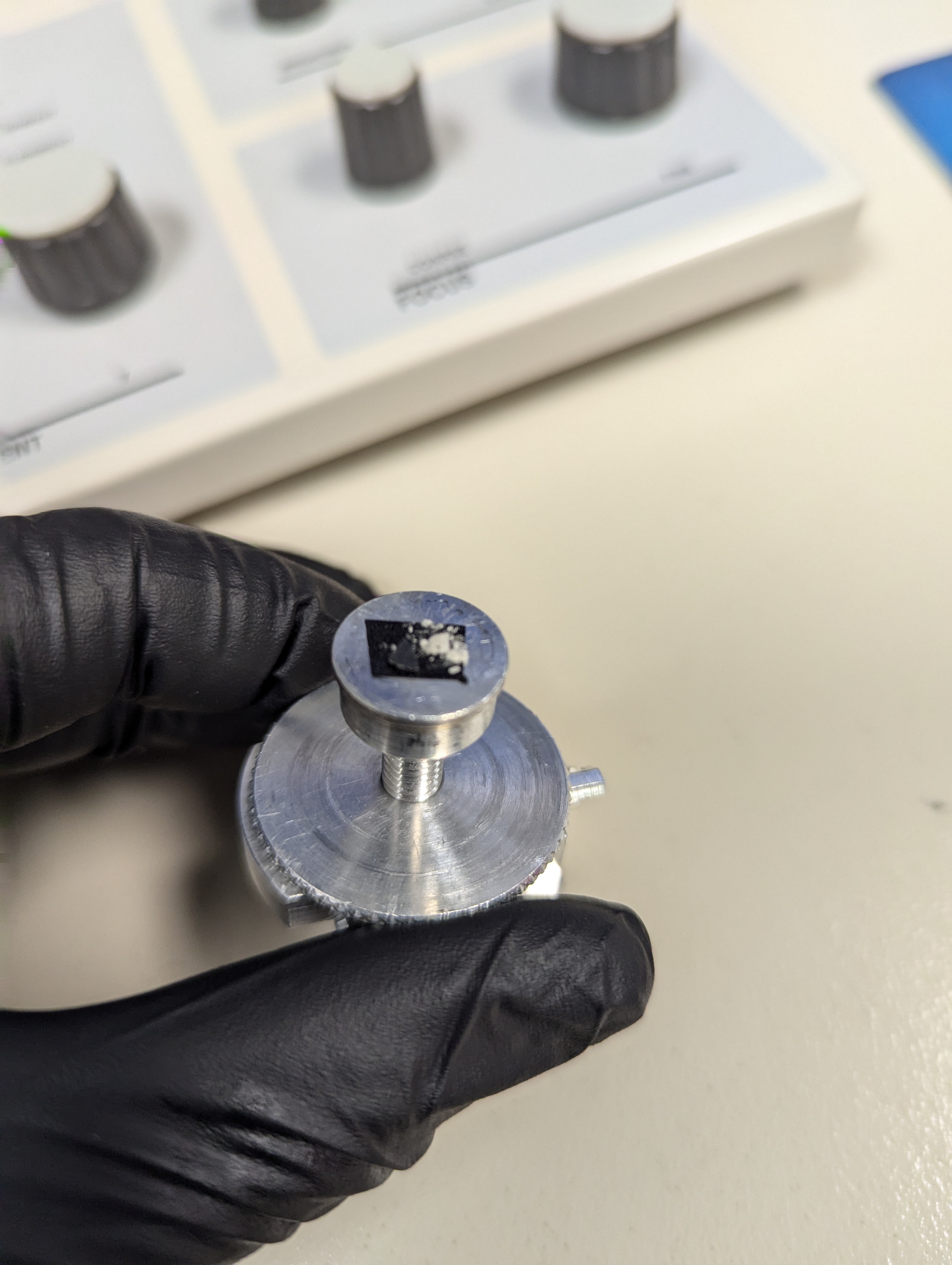 A coating sample on the 15 mm aluminum SEM stage, mounted with carbon tape and ready for the chamber.